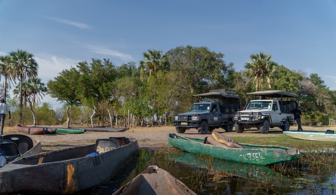Two safari vehicles parked by a lake with canoes