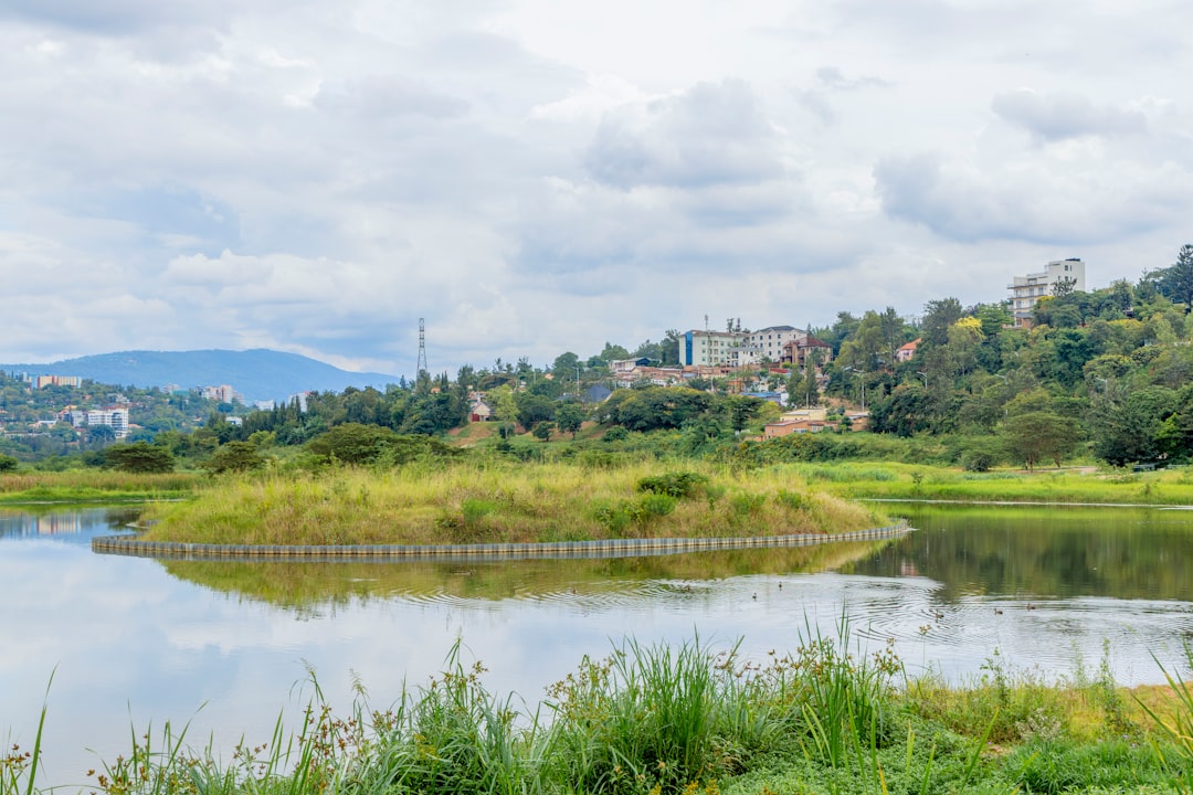 Lake with grassy island and buildings on a distant hill.