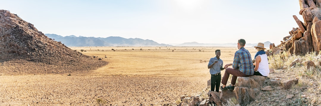 a group of people standing on top of a dry grass field