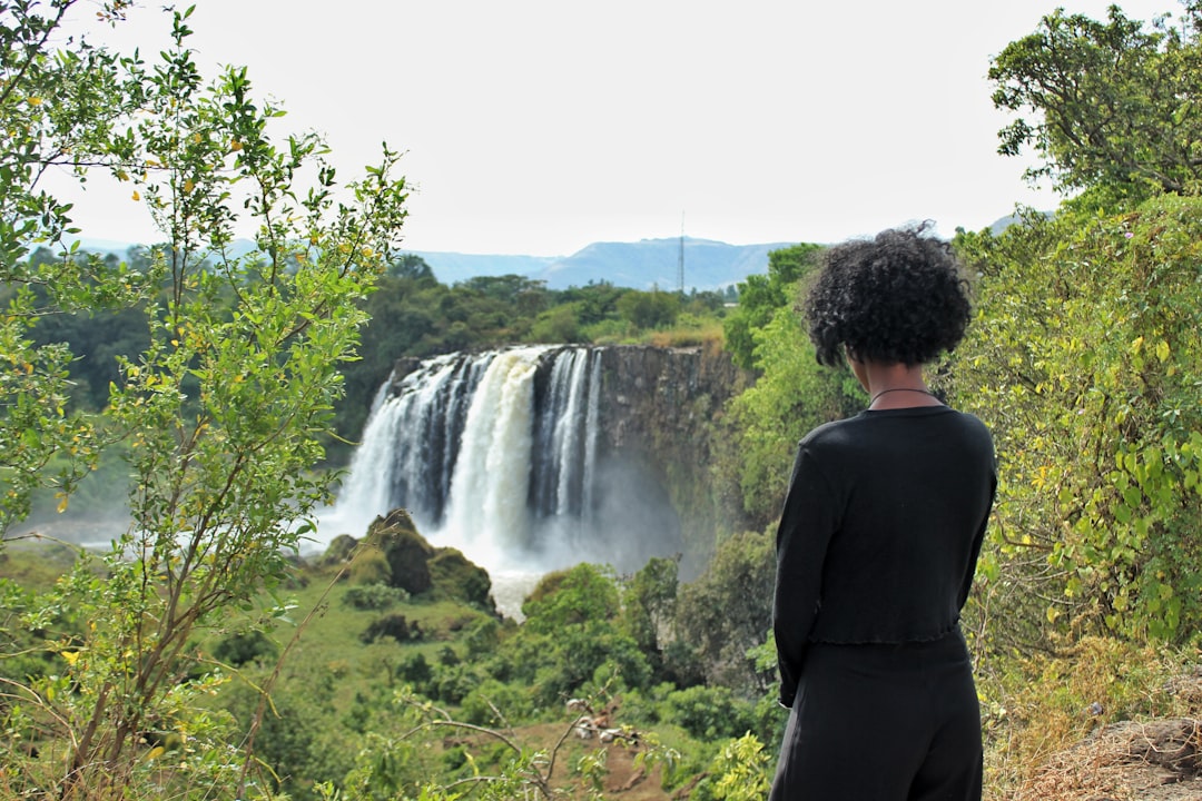 Woman with curly hair watching a majestic waterfall