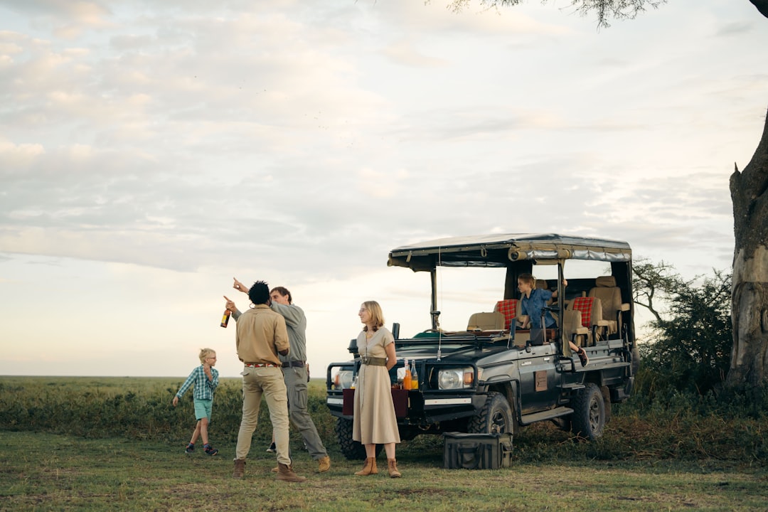 People gathered around a safari vehicle in a grassy field