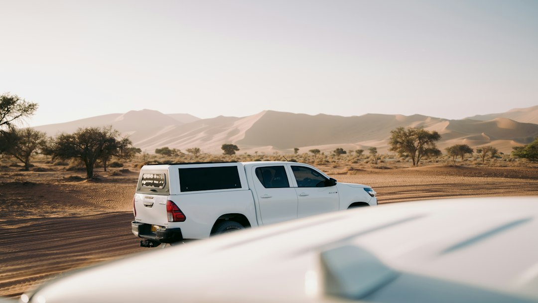 White pickup truck driving through a desert landscape