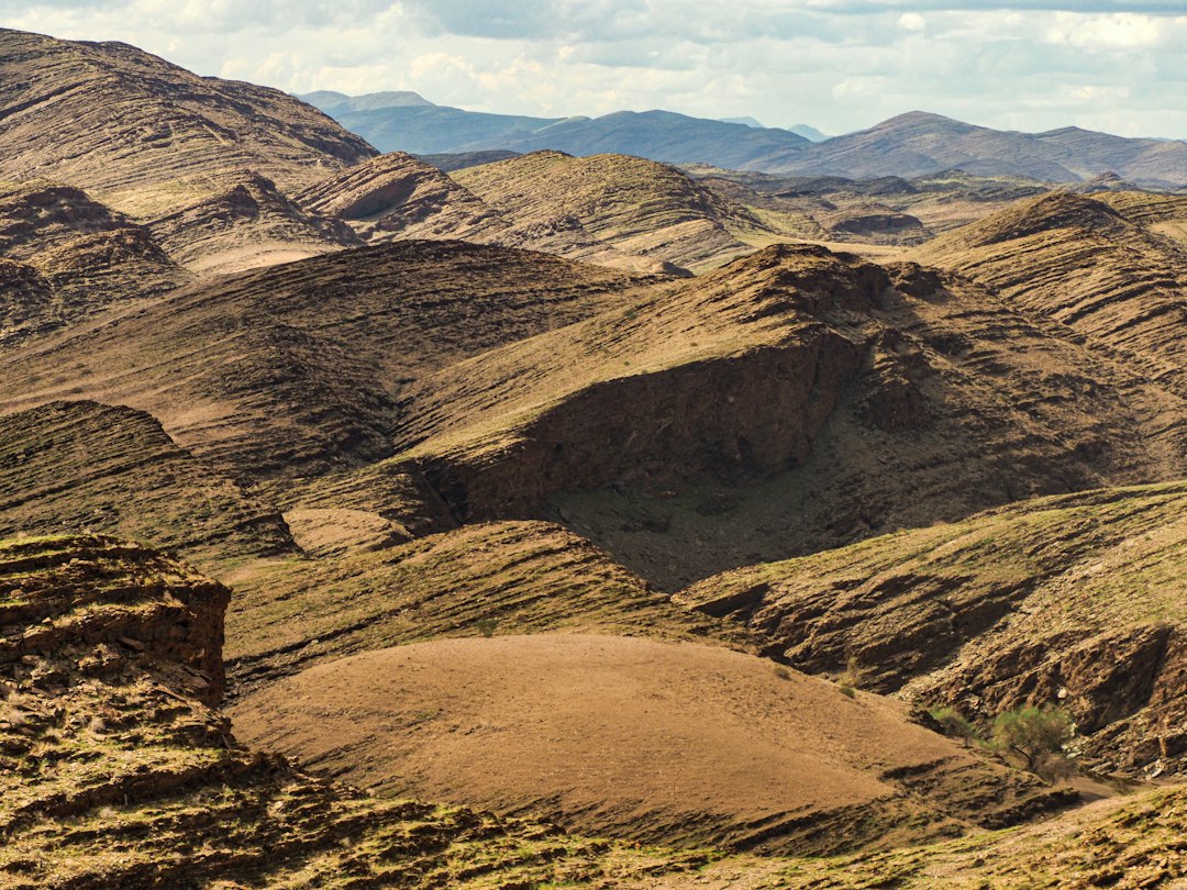 Arid mountainous landscape with rolling hills under a cloudy sky