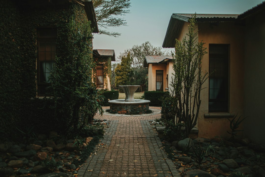 a brick walkway between two buildings with a fountain