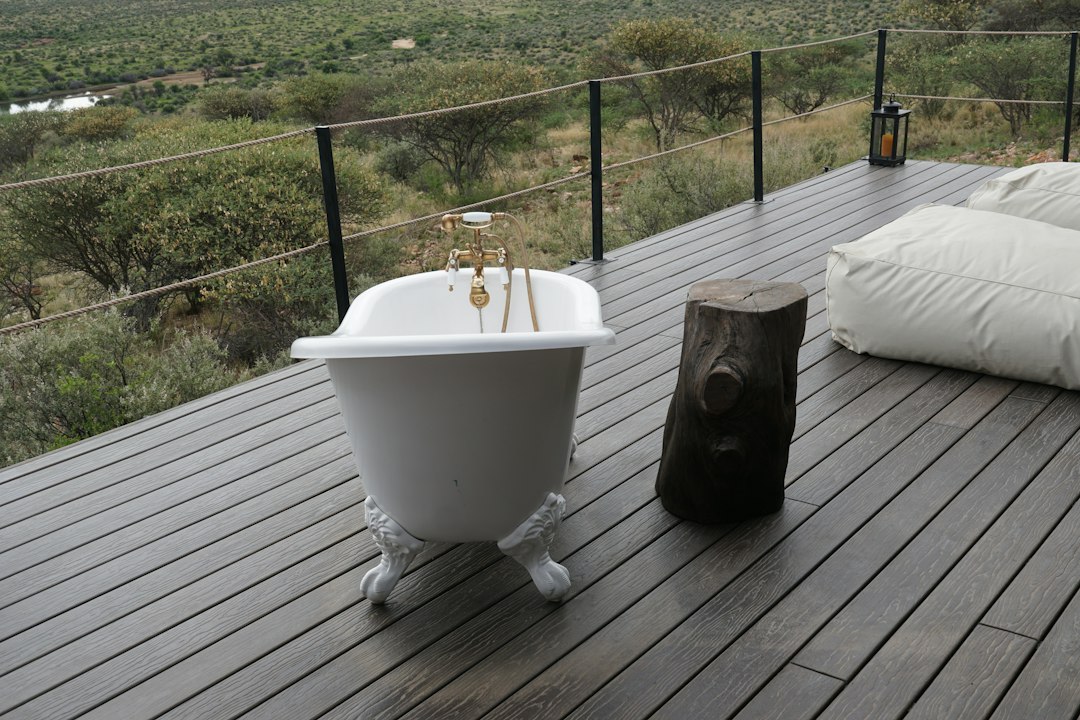 Bathtub on a wooden deck overlooking savanna landscape