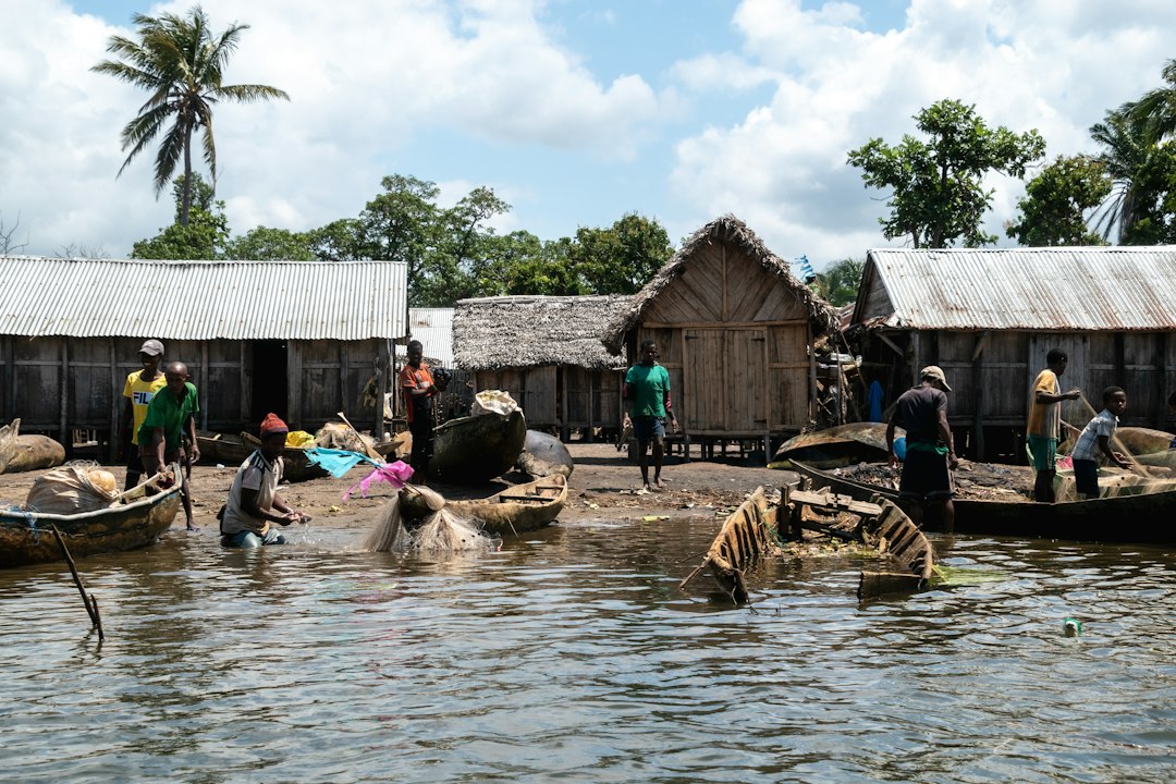 People stand outside huts on a watery landscape