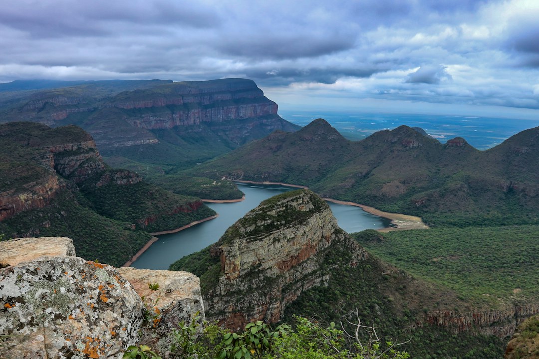 body of water and green mountain under blue sky