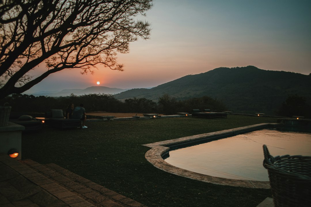 the sun is setting over a pool in the mountains