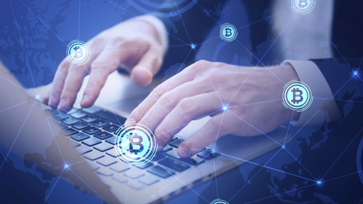 Manos que escriben en una laptop con símbolos de Bitcoin conectados en una red superpuesta