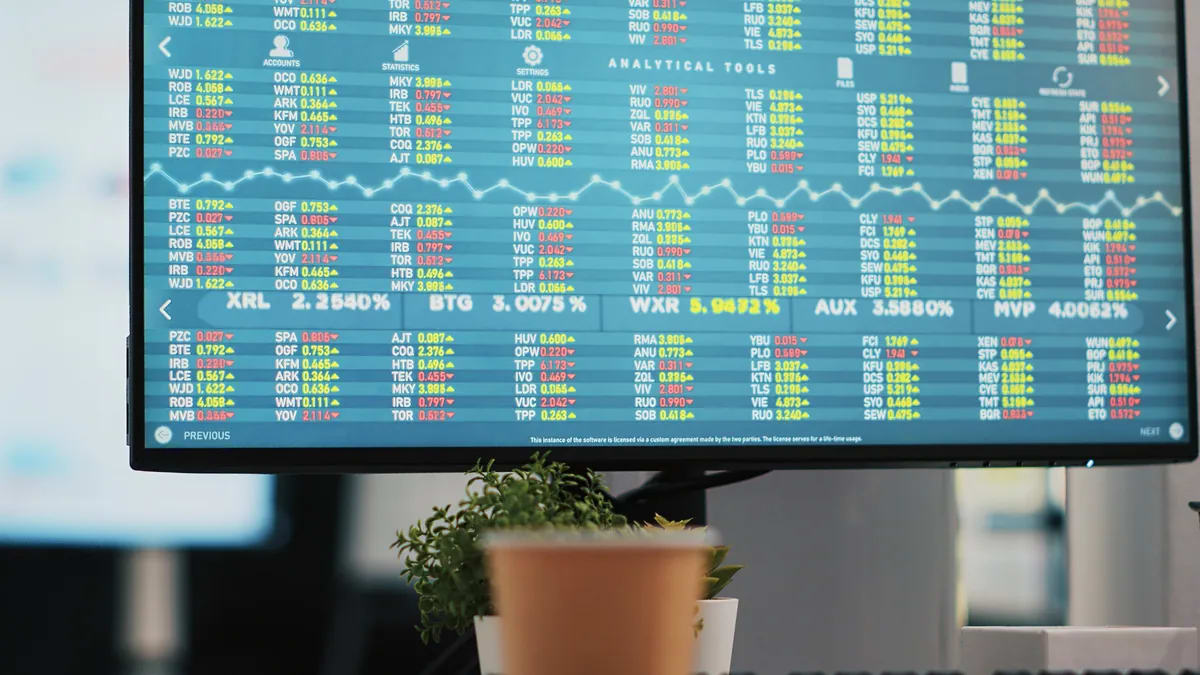 Monitor con una tabla de cotizaciones en una oficina, con una planta en primer plano