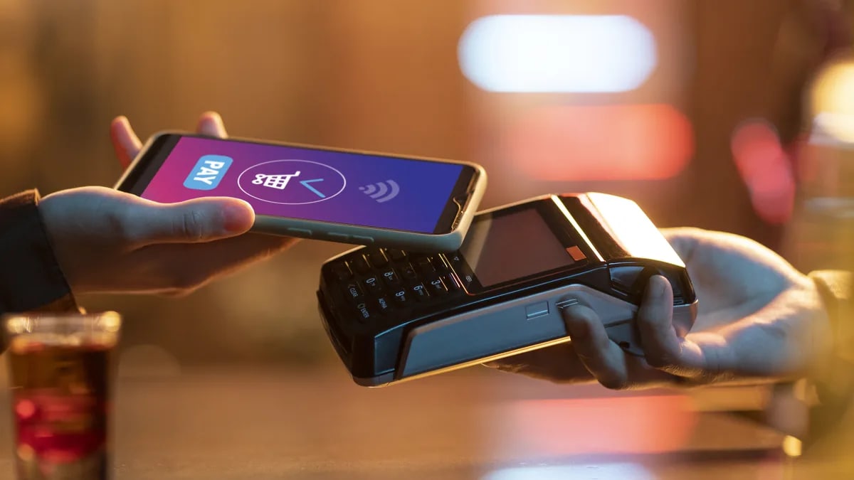 Pago con el celular acercado a una terminal punto de venta