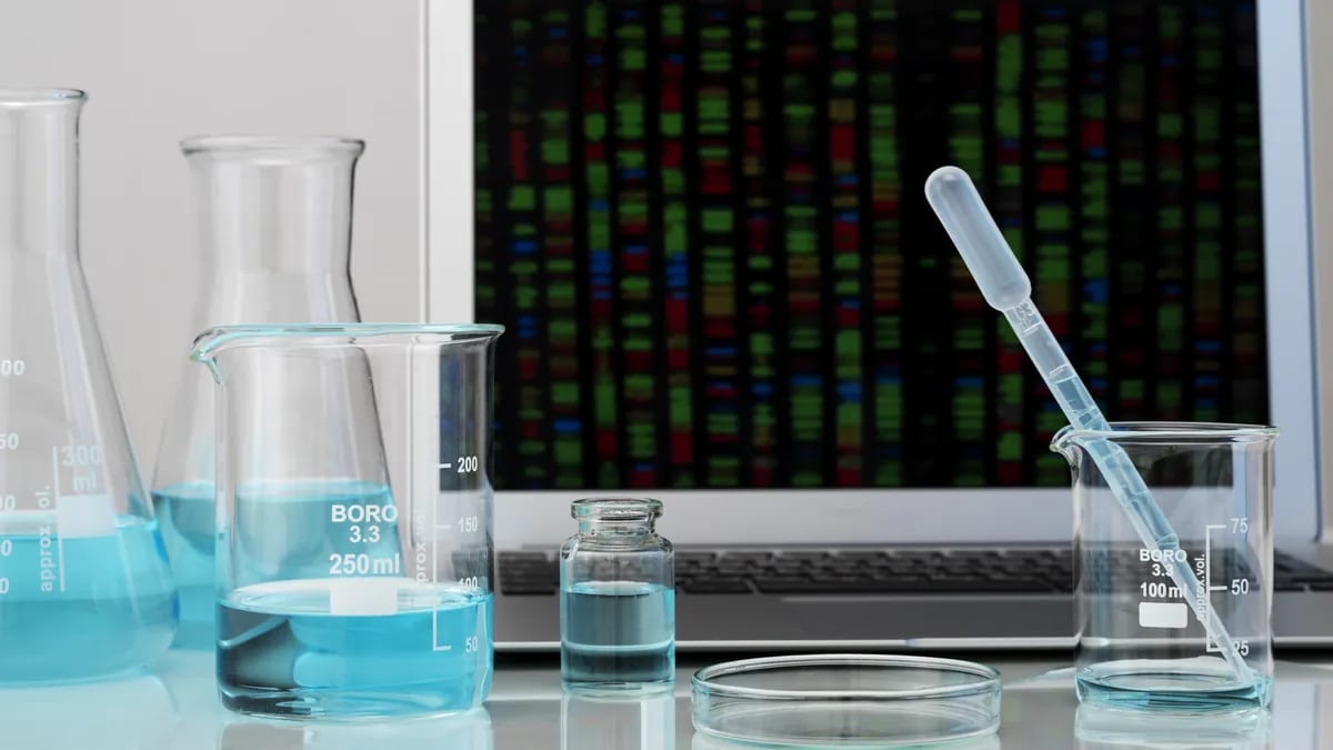 Material de laboratorio con líquido azul frente a una laptop
