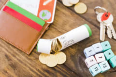 Cartera, monedas, llaves y una calculadora de piezas sobre una mesa de madera