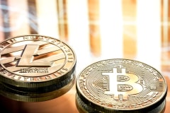 Monedas físicas de Litecoin y Bitcoin sobre un fondo cálido desenfocado