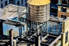 Azotea con tanques de agua de madera y estructuras metálicas en una ciudad