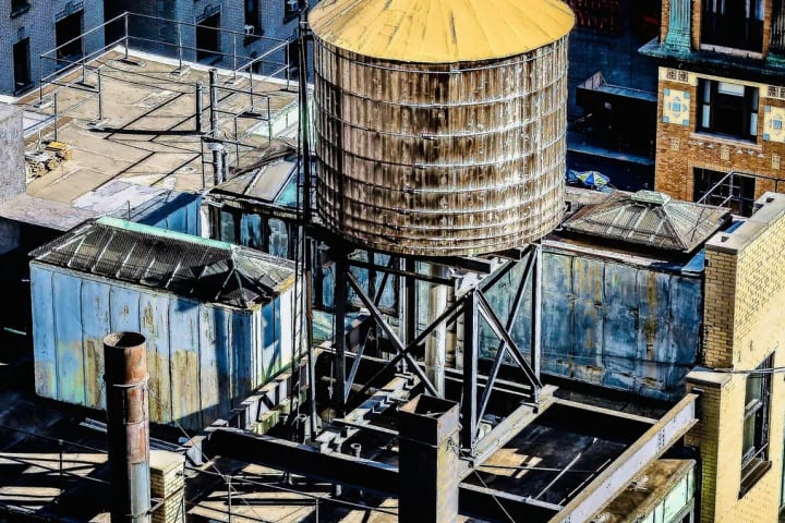 Azotea con tanques de agua de madera y estructuras metálicas en una ciudad