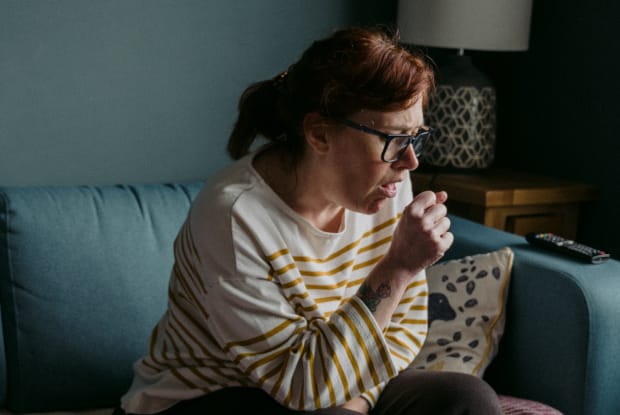 A woman coughing into her fist