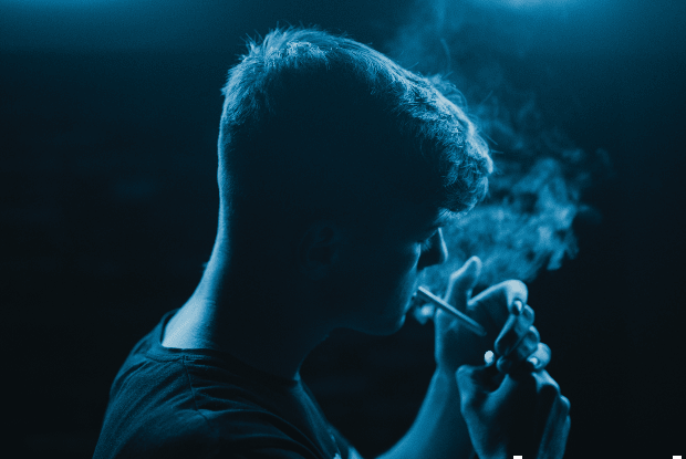 a man smoking underneath blue light