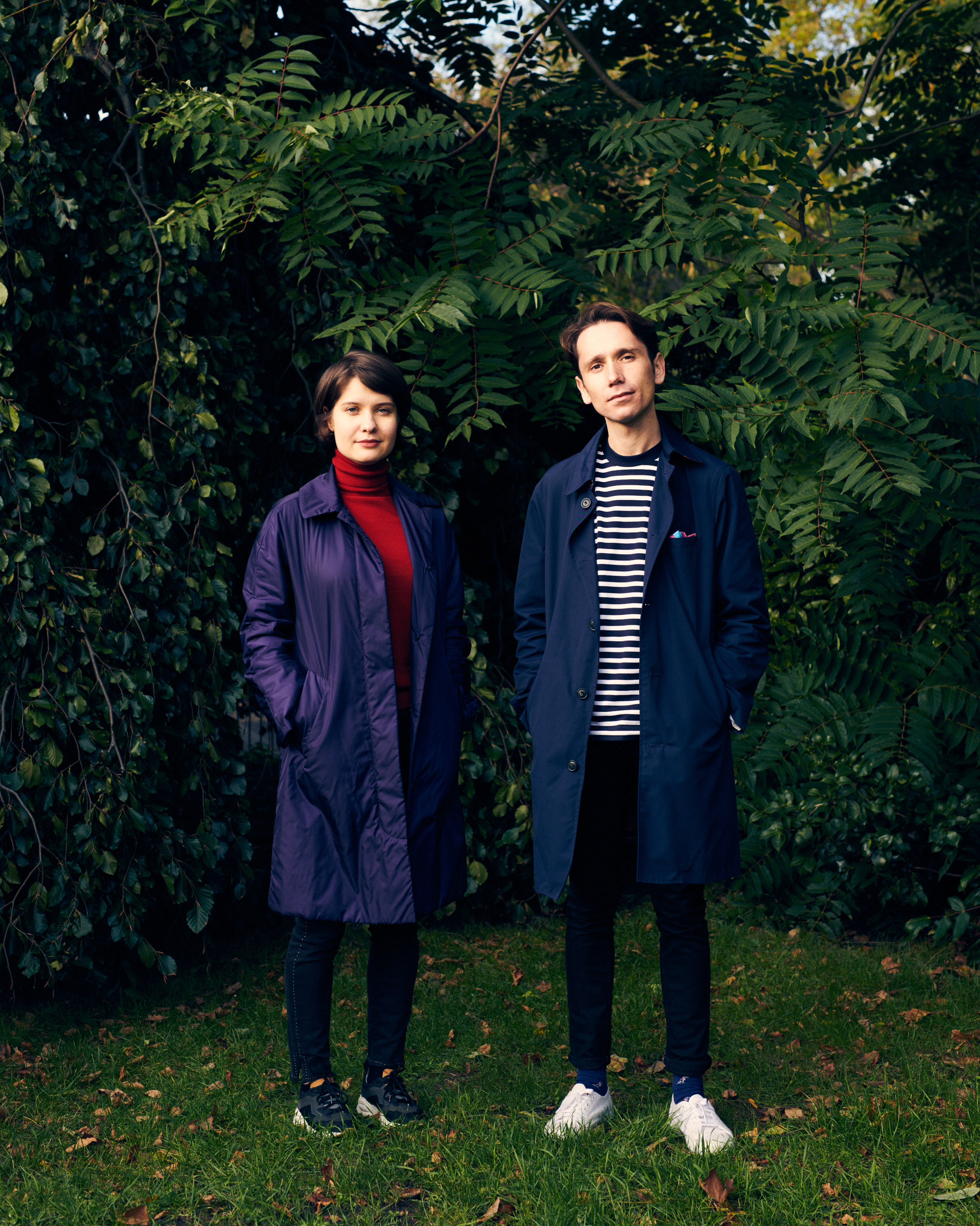 Dzmitry Suslau and Evgeniya Ravtsova standing in front of large greenery in a park.