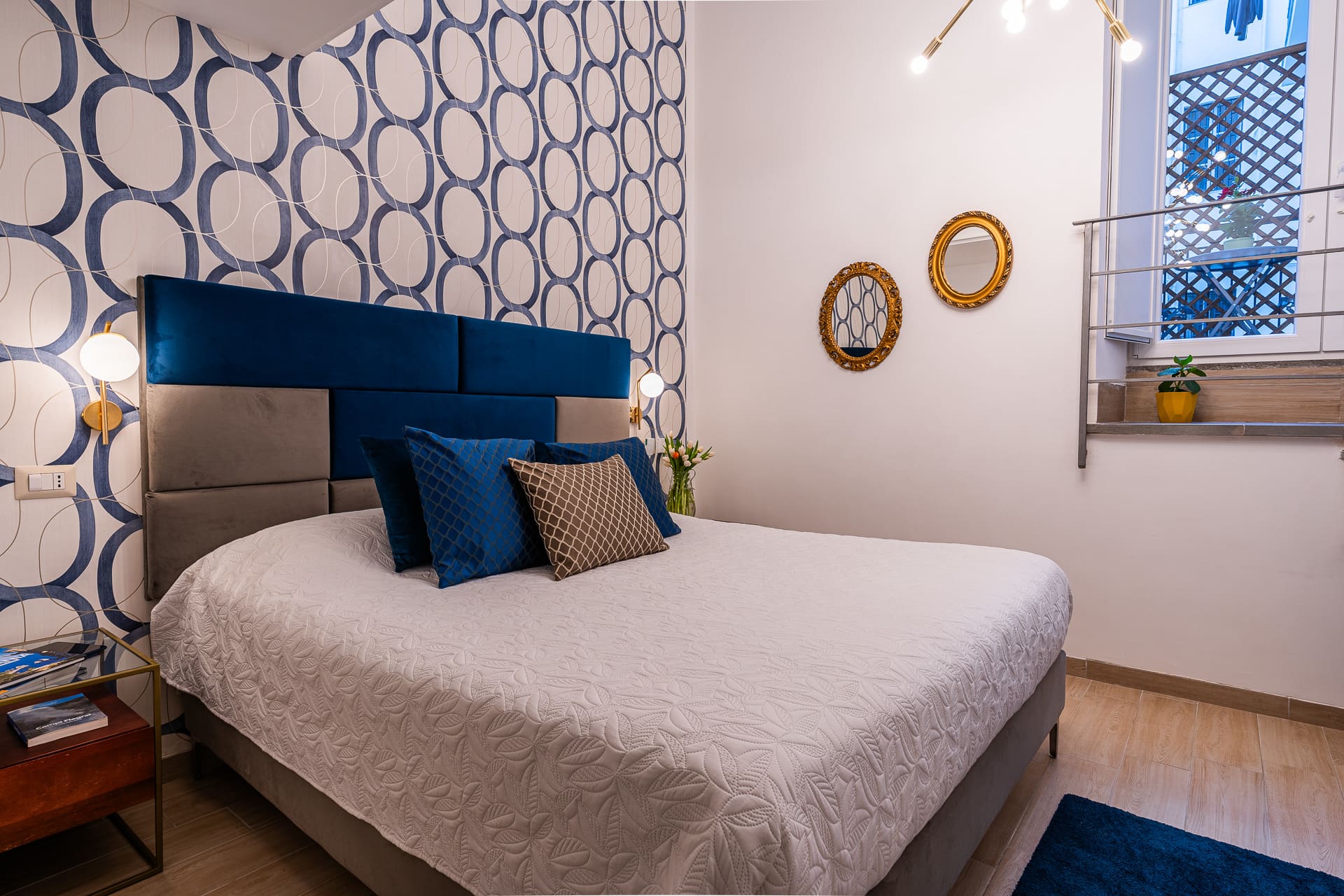 Suite Bella 'Mbriana: testiera in velluto blu con carta da parati a motivi ovali e specchi dorati, Daymoon House Vanvitelli
