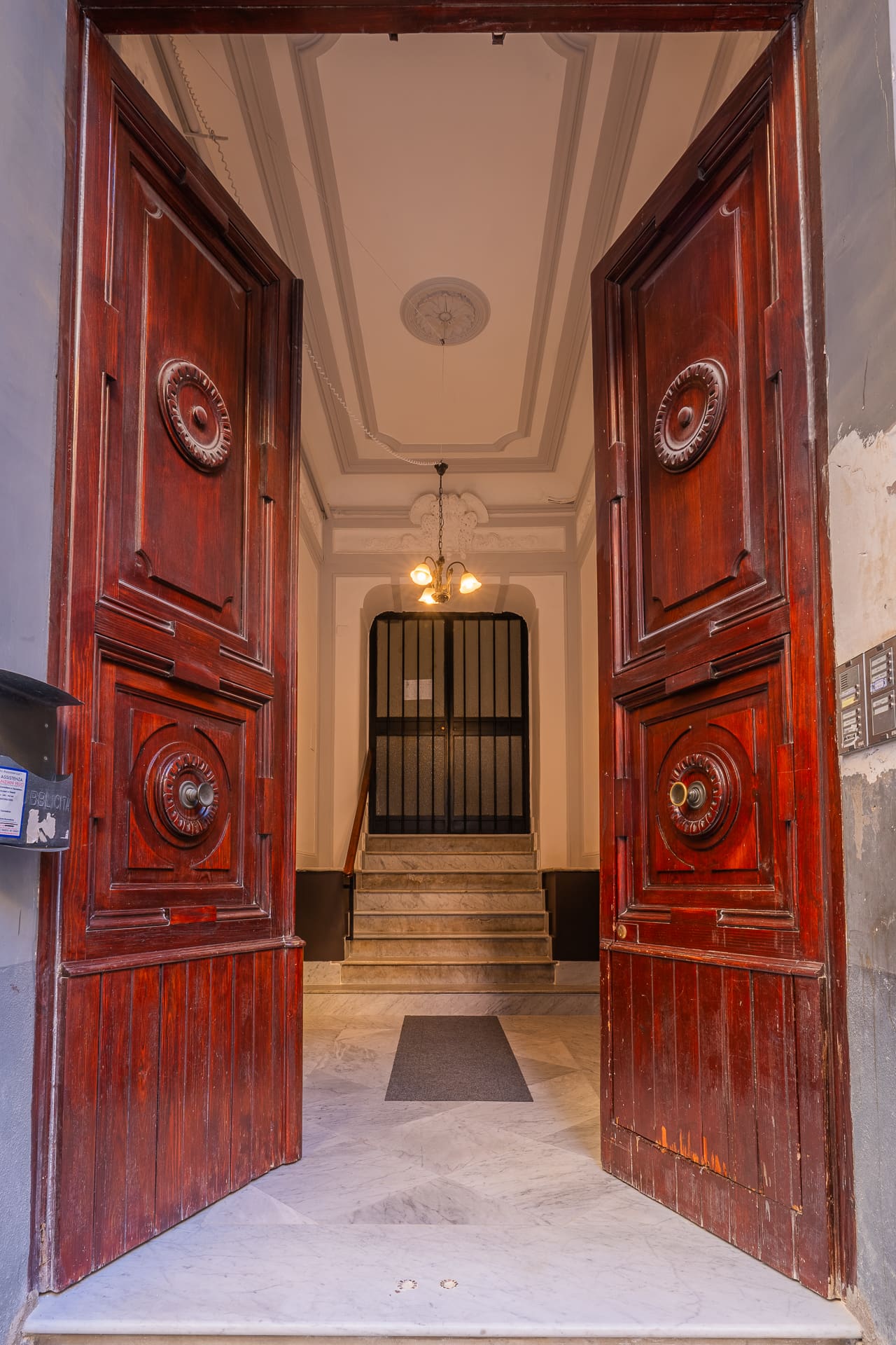 Ingresso storico del palazzo dei primi del '900 di Daymoon House Merliani, con portone in legno intagliato e scalinata in marmo
