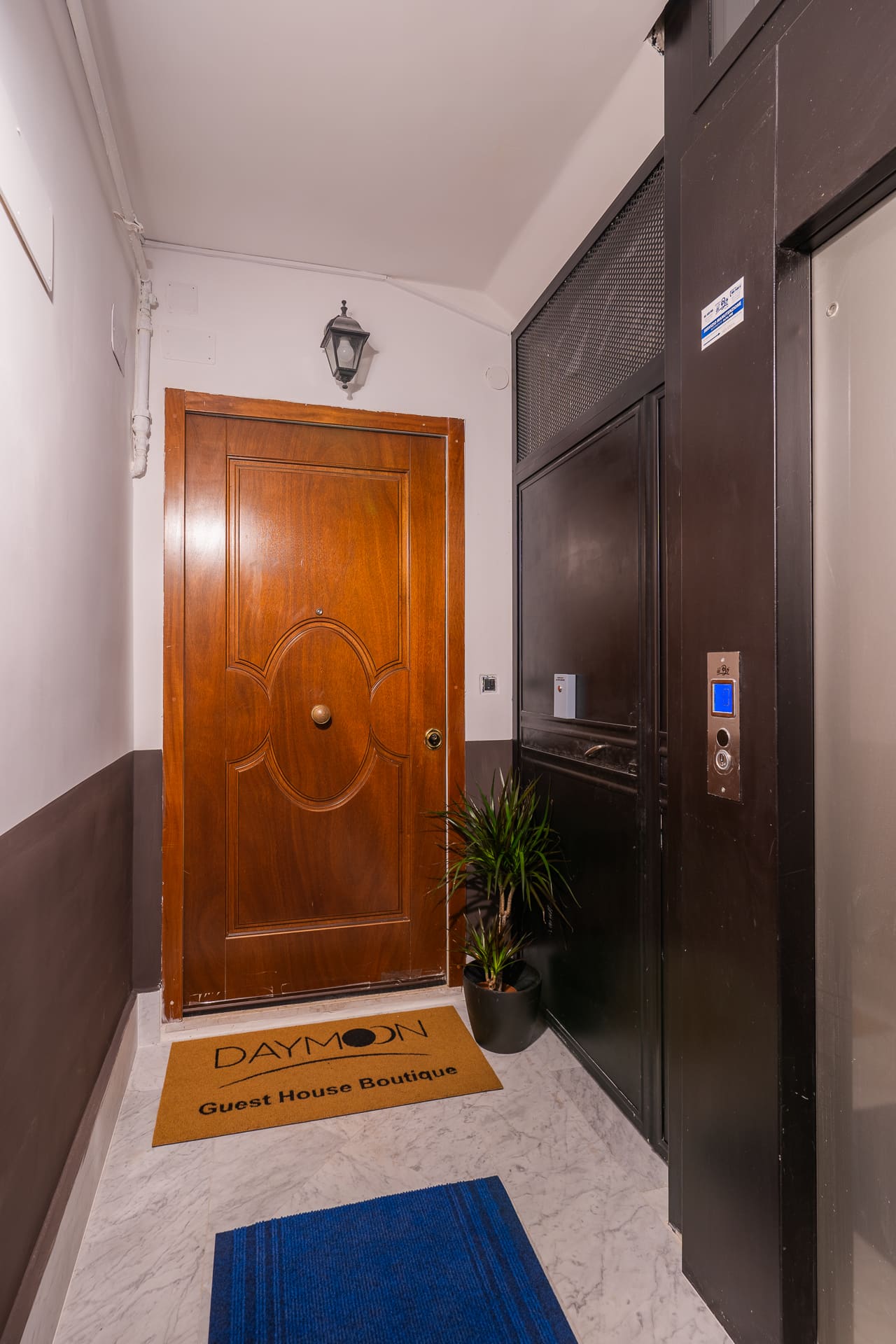 Porta d'ingresso dell'appartamento di Daymoon House Merliani, con zerbino di benvenuto e ascensore