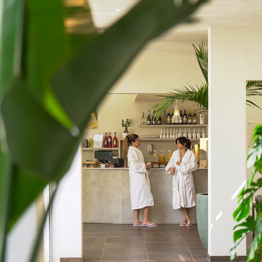 Il bar bistrot delle Terme di Agnano, con due ospiti in accappatoio al banco, tra piante tropicali