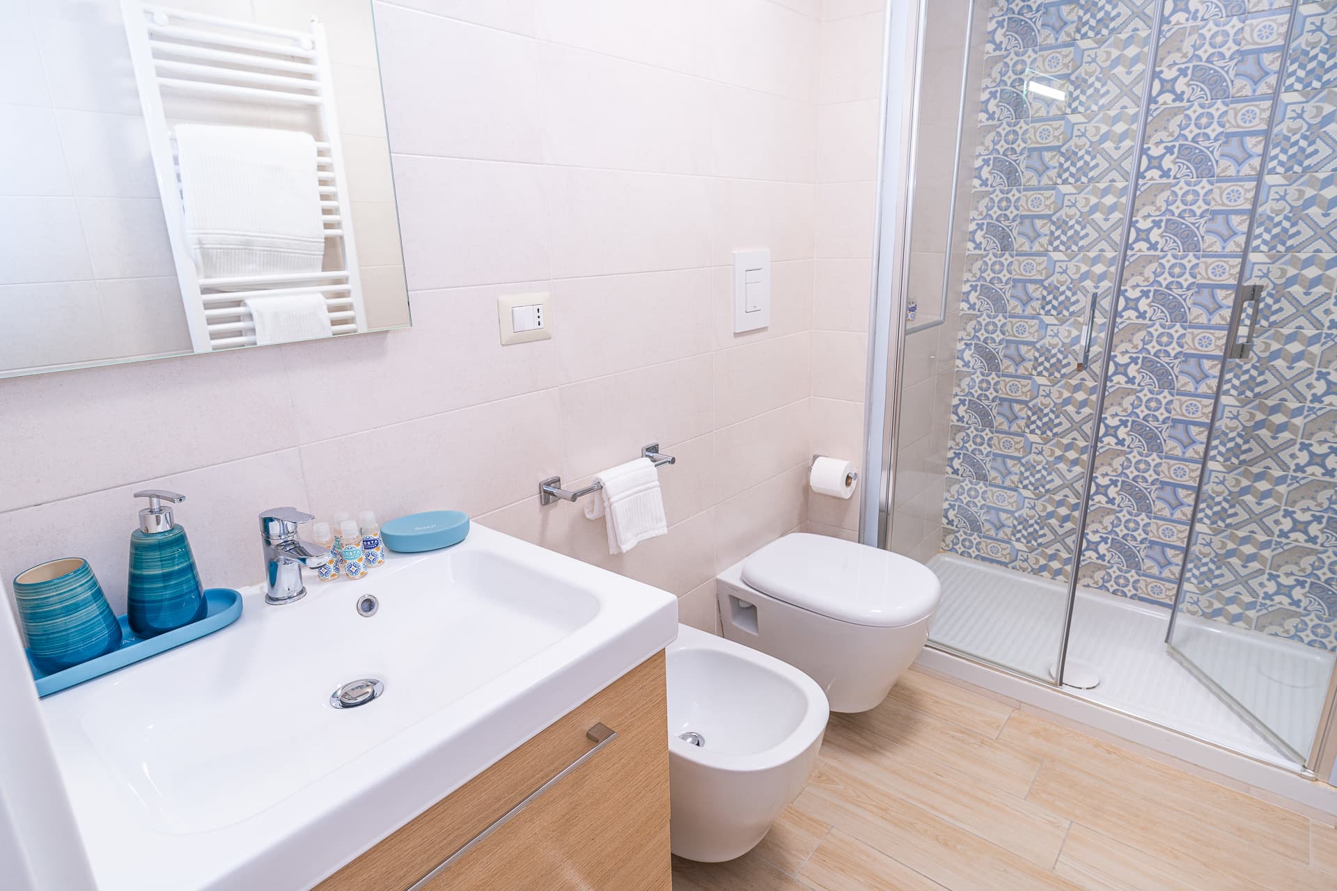 Bagno della camera Megaride con termoarredo, lavabo e doccia con maioliche azzurre