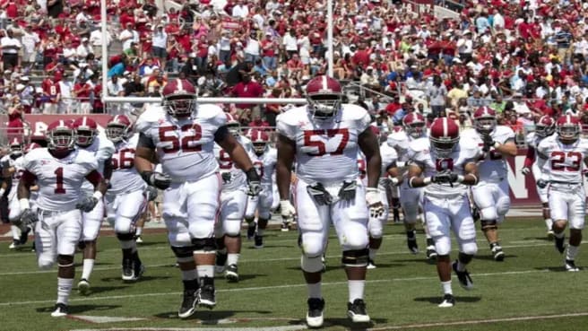 NFL Football team wearing white uniform in a game with fans in the background.