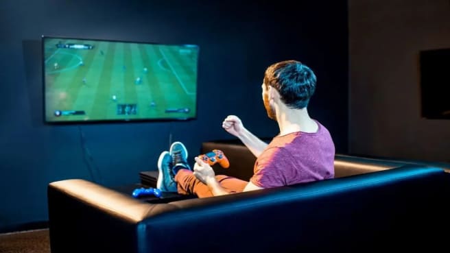 A man on the couch playing a video game on the PC.