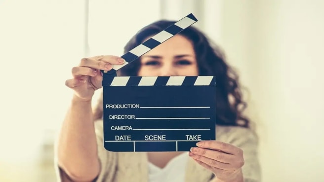 An actress hiding behind a movie clapper.
