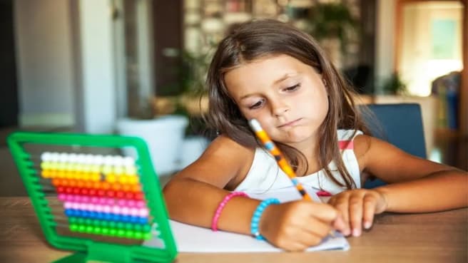 A little girl writing answers to a math question.