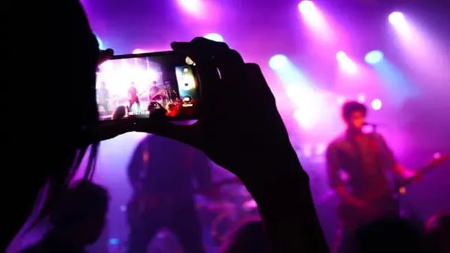 Typical Pop Culture moment of a fan picturing is a favorite music band with the smartphone.