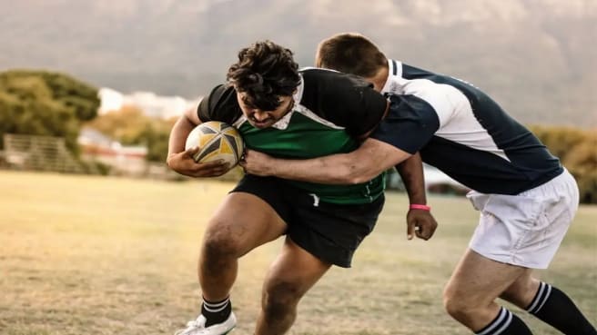 Two Rugby players are fighting on the ball during a rugby game.