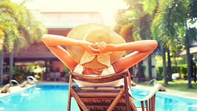 A woman is sitting in the pool and getting tanned in the summer.