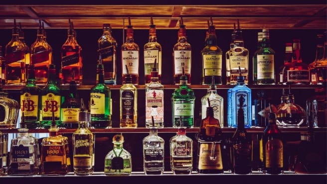 Many different bottles of Alcoholic drinks in a pub.