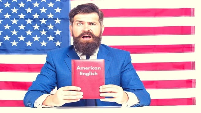 A funny American man holding a book of American English dialect with an American flag behind him.