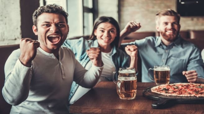 Three friends are sitting in a bar participating in bar trivia.