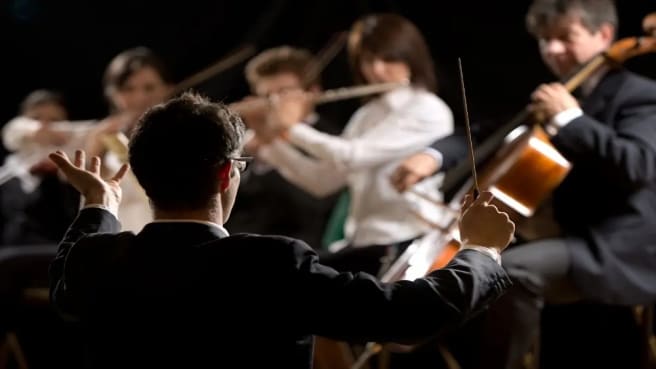 The conductor of the orchestra and the orchestra is playing classical music.