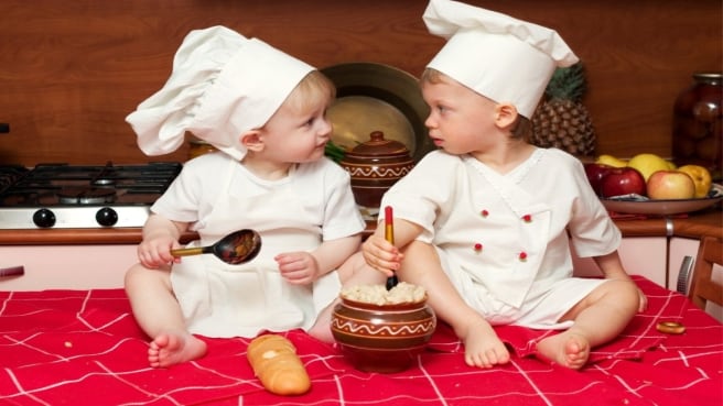 Two cute babies dressed up a chefs, cooking in the kitchen.