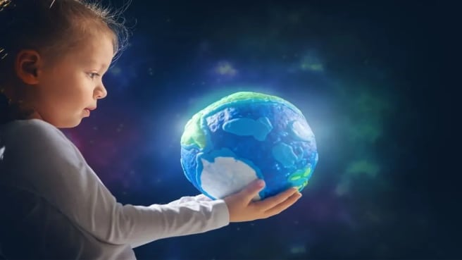 A little boy is holding a childish Earth in his hands.
