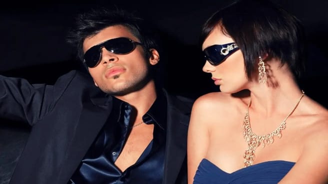 A Famous Couple of two celebrities, in a car, with dark sunglasses.