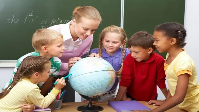 Kids and their geography teacher learning geography on the globes ball.