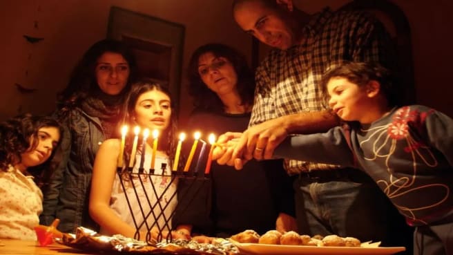 A Jewish family is lighting the Menorah on Hanukkah.
