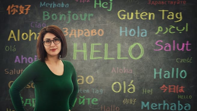 A language teacher with the word hello in many languages on the chalkboard.