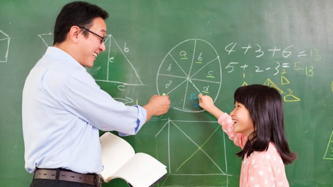 A 2nd-grade girl and her teacher are solving math questions for grade 2.