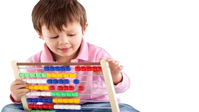 A cute 3th-grade boy playing with math toys for kids.