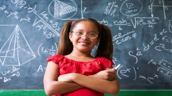 A cute 6th-grade girl in a red dress, with a math chalkboard behind her