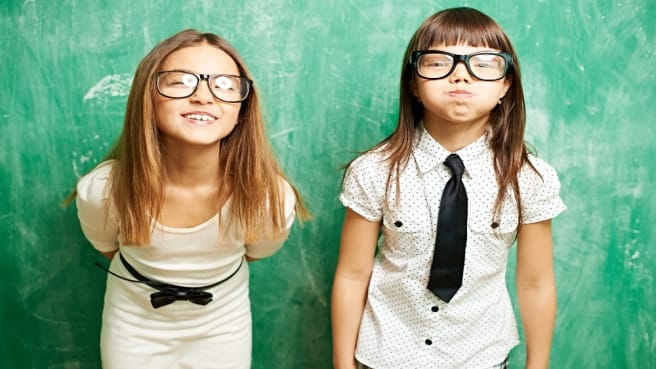 Two funny 7th-grade girls with glasses with a math chalkboard.