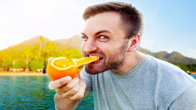 A man eating an orange and more food.